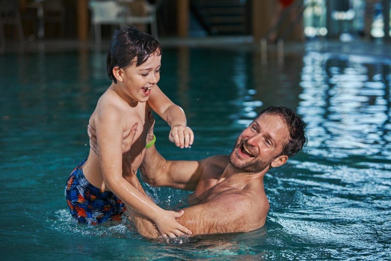 Otec hrajúci sa so synom vo vnútornom bazéne  - Hotel Sitno 