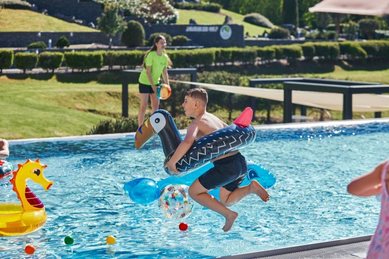 Dieťa skáče do vonkajšieho bazéna v areáli Hoteli Sitno - Trinity Hotels.sk 